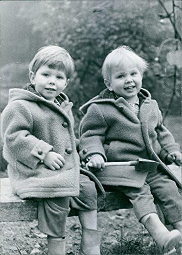 Гроздобер фотографија од фотографија на две деца како седи на клупа, облечена во јакна, насмеана.